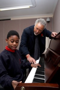 Sir Tom Jones walesi énekes és egy zongorázó kisfiúval a Nordoff Robbins Zeneiskolában Londonban 2010. november 18-án 