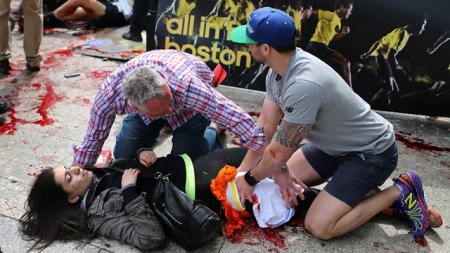 Sérült asszonyon segítenek a bostoni maraton helyszínén az ott történt két robbantás után 2013. április 15-én